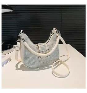 Detail of hobo bag with silver rhinestones and a metallic bow on a white surface