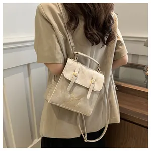 Detail of beige PU leather backpack featuring butterfly embroidery and gold metal buckle