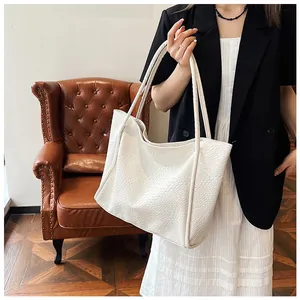 Detail of white woven tote bag showing geometric texture on a vintage leather chair