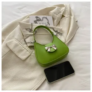 Détail du sac demi-lune vert vif avec nœud en métal argenté et bandoulière chaîne