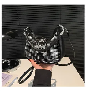Detail of black crescent hobo bag featuring silver rhinestones and metal bow accent