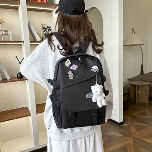 Détail d'un sac à dos noir avec des épingles d'astronaute et un pendentif ours en peluche
