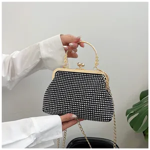 Close-up of sparkling silver rhinestones on black evening clutch with gold metal handle