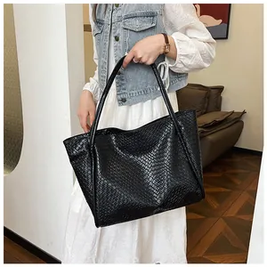 Detail of black faux leather tote bag showing textured animal skin embossing and straps