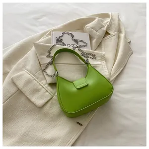Vue détaillée du sac hobo vert vif sur une veste en tweed avec une chaîne argentée