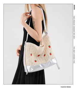 Detail of straw tote bag with red strawberry embroidery and silver metallic trim