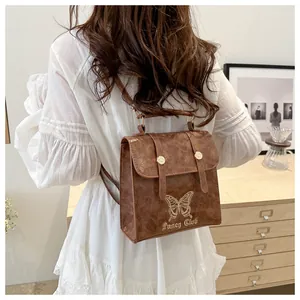 Detail of brown leather backpack with butterfly embroidery and golden metal hardware