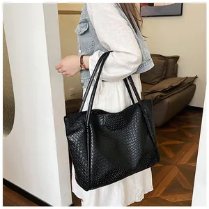 Detailed close-up of large black tote bag with intricate woven texture and leather finish