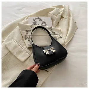 Détail du sac croissant noir avec nœud métallique argenté et bandoulière chaîne