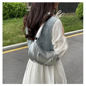 Detail of silver metallic crescent bag with adjustable buckles and textured finish