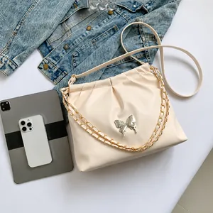 Détail du sac seau en PU beige avec boucle papillon argentée et bandoulière chaîne