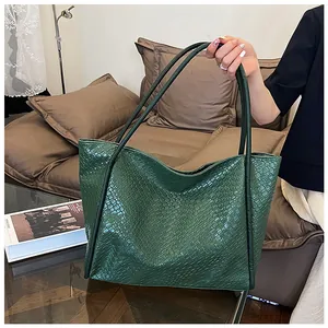 Detail of dark green tote bag featuring woven texture and long handles for shoulder use