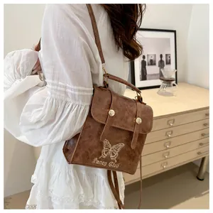 Detailed back view of a brown leather backpack with butterfly embroidery and gold clasp
