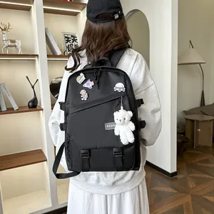Détail du sac à dos en nylon noir avec des épingles d'astronaute et un ours en peluche