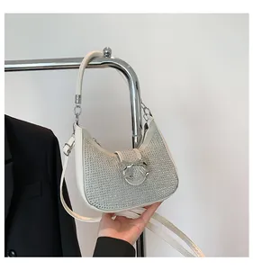 Close-up of white crescent bag with silver rhinestones and a metal bow detail