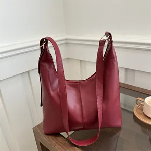 Retro burgundy leather tote bag with dual shoulder straps and gold rings in lifestyle setting