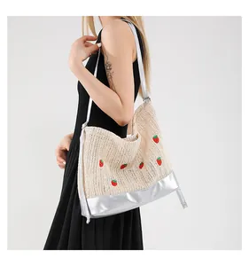 Detail of strawberry embroidery on ivory straw tote with silver metallic straps