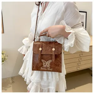 Detailed view of vintage brown leather bag featuring butterfly embroidery and Fancy Club text