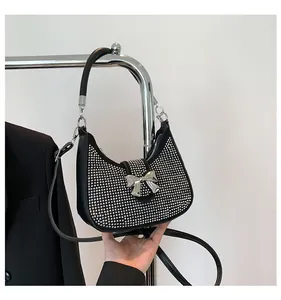 Detail of black crescent hobo bag featuring silver studs and a metallic bow clasp