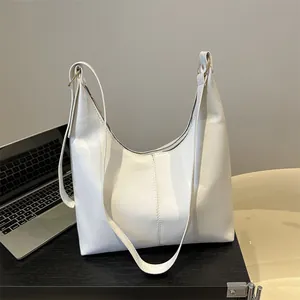 White leather hobo shoulder bag with quilted details on a black office desk setup