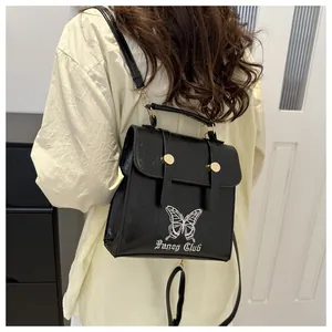 Detail of black glossy backpack featuring white butterfly embroidery and gold-tone hardware