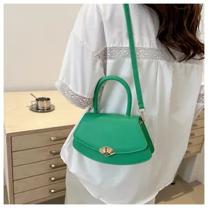 Détail du sac bandoulière vert avec fermoir doré en forme d'éventail et texture raffinée
