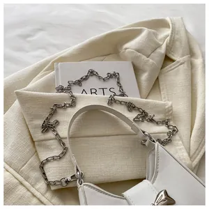 Détail du sac en cuir synthétique blanc avec chaîne en métal argenté et boucle élégante