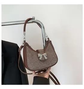 Detail of a brown crescent shoulder bag with silver rhinestones and a metal bow buckle