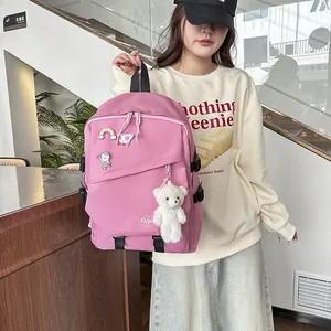 Détail du sac à dos rose avec broches de dessin animé et pendentif d'ours en peluche