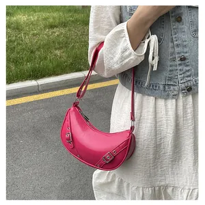 Close-up of a hot pink saddle bag with silver rivets and buckle in a casual outfit