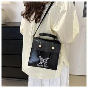 Close-up of black leather bag featuring white butterfly embroidery and artistic lettering