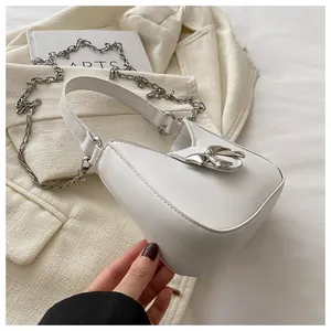 Détail d'un sac à bandoulière en cuir blanc avec boucle nœud en métal argenté et chaîne