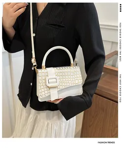 Elegant white crossbody bag featuring gold grid texture and large decorative buckle detailing