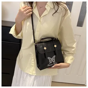 Detail view of black square crossbody bag with white butterfly print and gold buckle detail
