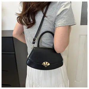 Détail d'un sac bandoulière noir demi-lune avec fermoir doré et texture cuir fin