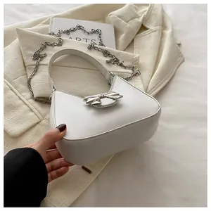 Gros plan du sac demi-lune blanc avec nœud en métal argenté et bandoulière chaîne