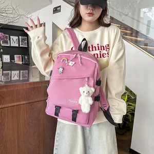 Détails du sac à dos rose avec des épingles arc-en-ciel et un ours en peluche blanc