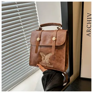 Detail of vintage brown PU leather backpack with gold butterfly and Fancy Club embroidery