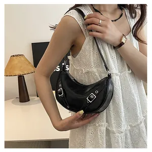 Detail of a vintage black crescent saddle bag with metallic buckles on a lace dress