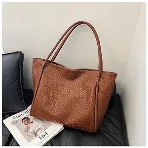Close-up of brown woven tote bag with leather straps on a sofa, large capacity