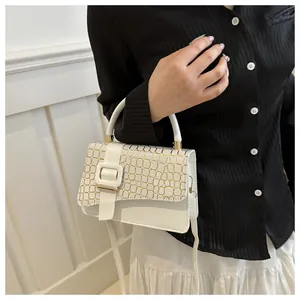 Close-up of white square shoulder bag with gold crocodile texture and metal clasp buckle