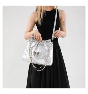 Détail du sac argenté métallisé avec boucle nœud sur robe sans manches noire