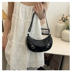 Detail of a black half-moon saddle bag featuring silver eyelet buckles and smooth leather