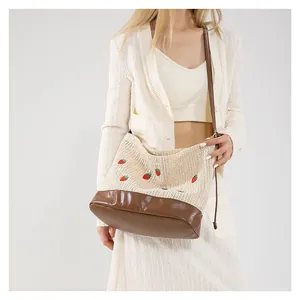 Handwoven straw bucket bag with strawberry embroidery and brown leather strap for summer