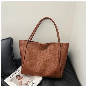 Detail showing high-capacity brown woven tote bag texture and slender shoulder straps