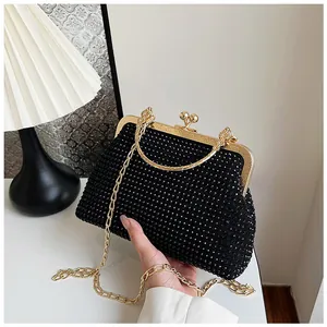Detail of elegant black rhinestone clutch bag with gold metal clasp and chain strap