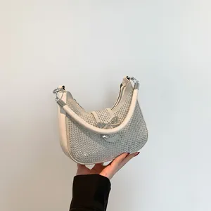 Chic silver rhinestone hobo underarm bag with a metallic bow detail and cream handle