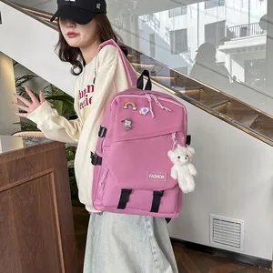 Détail d'un sac à dos d'école en toile rose avec badges de dessin animé et ours en peluche