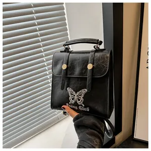 Detail of butterfly embroidery and Fancy Club text on black textured leather backpack