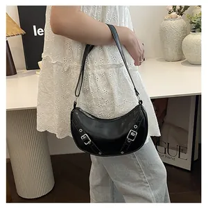 Close-up of black crescent saddle bag with silver metal buckles and eyelet details